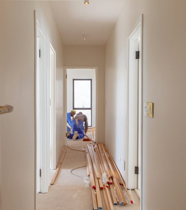 Byggarbetare utför renovering i ett hem med verktyg och skyddsutrustning.