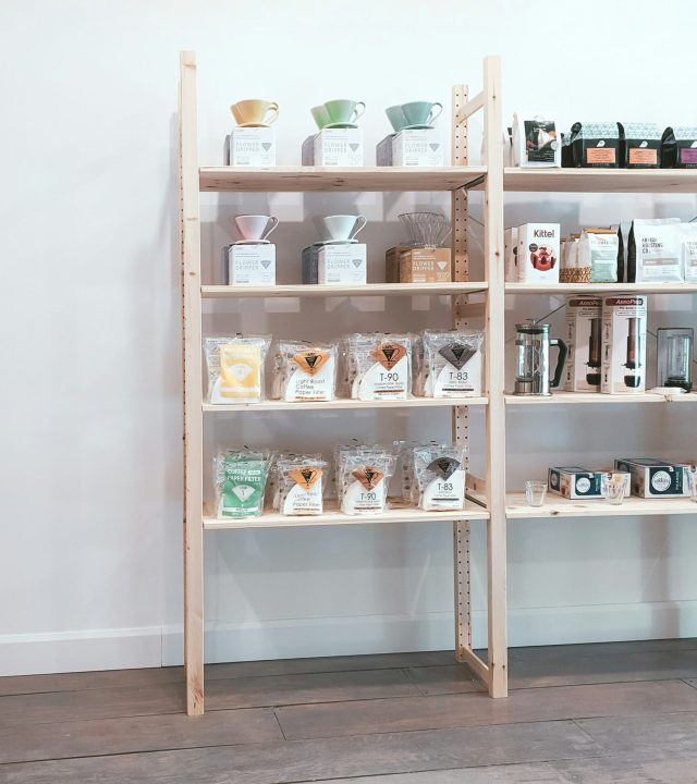 Ljusa butikshyllor och varor fotograferade inifrån butiken.