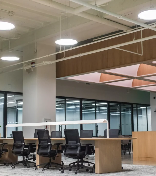 Ljust och modernt kontor med skrivbord, stolar och datorer.